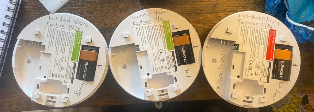 Smoke alarms with installation and testing dates written on them as part of smoke alarm inspections and maintenance in Bristol by Peregrine Electrical
